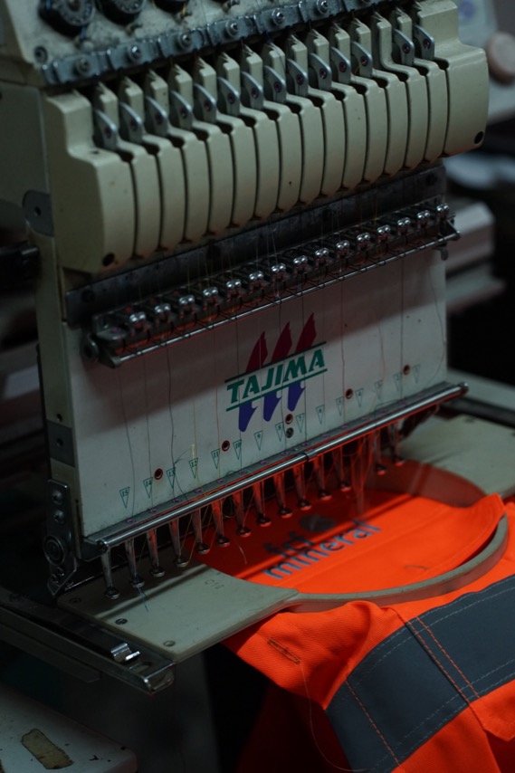 Embroidery machine stitching a branded garment